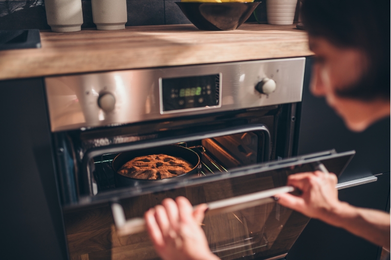Person checking bread baking in an oven, representing the challenge of finding real keto bread